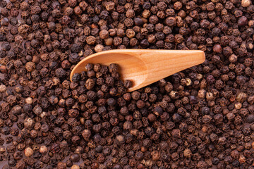 black pepper peas in a wooden spoon and scattered isolated on a white background