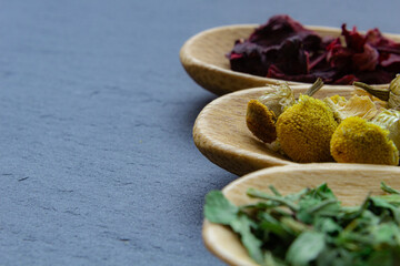 Spices background on wooden spoons. Parsley, chamomile, hibiscus