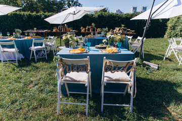 Banquet table setting and decoration. Cutlery on the table. Blue interior decoration. Tables at the outdoors.
