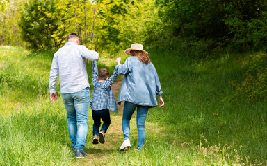 Back view of young parents on walk with their child at countryside, copy space