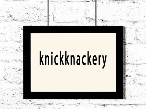 Black frame hanging on white brick wall with inscription knickknackery