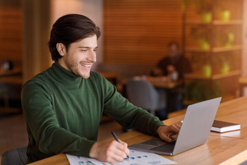 Entrepreneur checking on marketing reports online, cafe interior