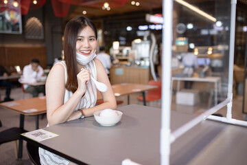 Asian woman sitting separated in restaurant eating food .keep social distance for protect infection from coronavirus covid-19, restaurant and social distancing concept.