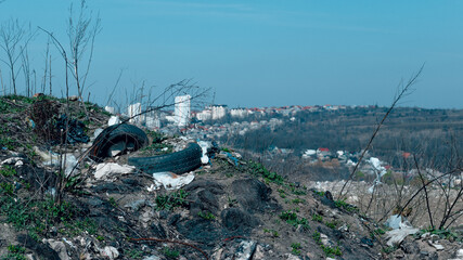Field covered with garbage and plastic bags thrown and scattered by the wind at the city background.