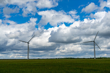 Photography of two wind turbines with cloudy sky in the background during sunny day