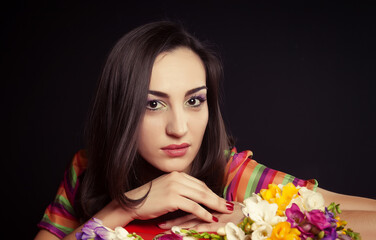 Fototapeta premium Young woman brunette in a bright dress posing in Studio on black background. Glamur and fashion.