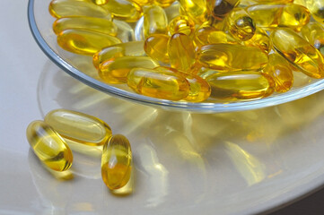 Fish oil capsules on a glass plate. A lot of vitamin omega 3. Close-up.