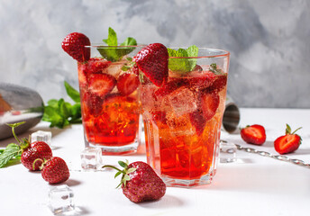 Strawberry mojito and ingredients on white wooden background