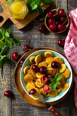 Tiny pancakes trendy food. Mini pancakes with cherries and honey on a rustic wooden table. Top view flat lay background.