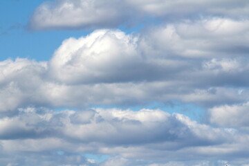 White fluffy clouds on a background of blue sky in summer. The concept of weather and climate.