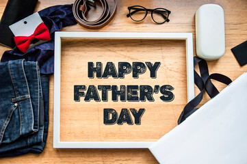 Greeting with a happy father's day on a wooden background with a white frame, glasses and gifts