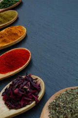 spice background on wooden spoons. Seasoning texture. Hibiscus, black pepper, paprika, cumin, curry, parsley