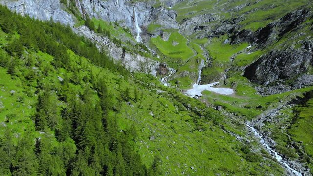 Aerial: drone flying over scenic high waterfall lush green valley and mountain stream on the italian Alps. Tourism destination hiking outdoors activity. Pis waterfall near Torino, Piedmont, Italy