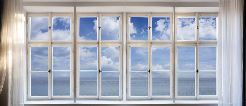 View of calm sea and blue sky background through old window concept. Retro white window