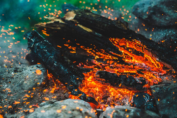 Vivid smoldered firewoods burned in fire close-up. Atmospheric background with orange flame of...