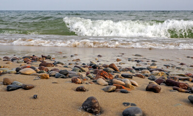 Fototapeta na wymiar Kleine Steine am Strand mit Wellen 