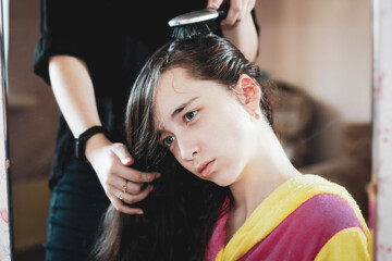 Fototapeta premium Portrait of a Beautiful girl in front of a mirror, which the stylist combs her hair.