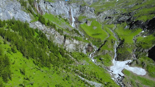 Aerial: drone flying over scenic high waterfall lush green valley and mountain stream on the italian Alps. Tourism destination hiking outdoors activity. Pis waterfall near Torino, Piedmont, Italy