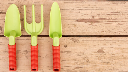 Garden tools of green color lie on the painted boards of the bench
