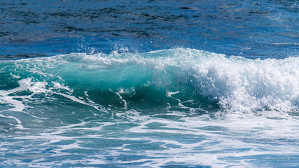 Vague déroulant sur un spot de surf avec de l'écume blanche et des embruns un jour ensoleillé en Guadeloupe