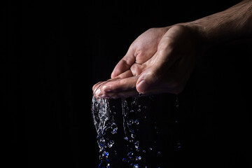 Water pours from two hands on a black background. Pure natural water. Water purification concept