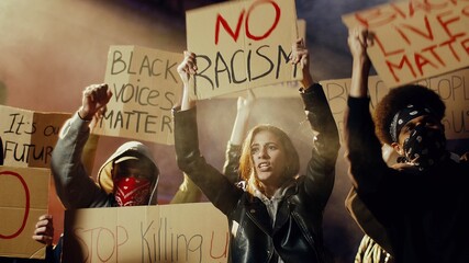 Male and female young multiethnic protesters in smoke screaming mottos and slogans with posters for...