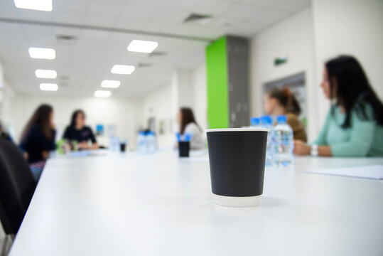 paper cup with coffee on a table in a meeting room. corporate discussion company development. Seminar and training of managers.
