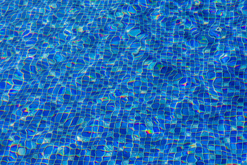 Blue and bright water in mozaic swimming pool with sun reflection background