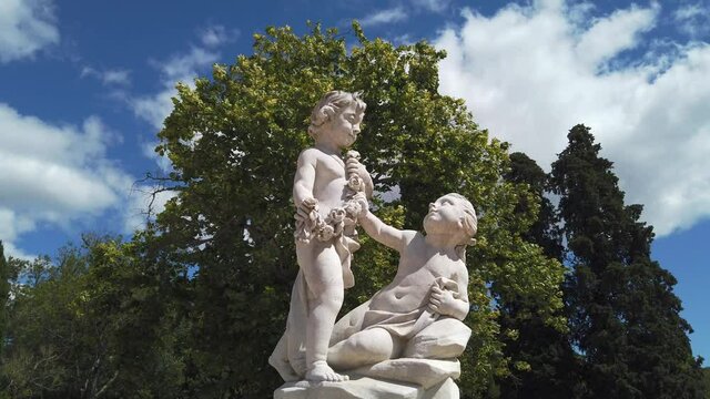 A marble statue with two kids in a garden.