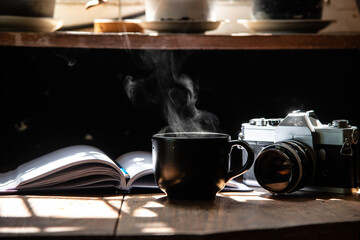 morning light refreshing black cup of hot coffee and stream with silver vintage camera and white page writing diary on wood table focus on camera stock photo