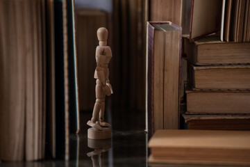 A drawing mannequin in between a bunch of old upright books © charlfolscher