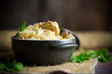 boiled rice with vegetables and meat in a ceramic bowl on a wooden table