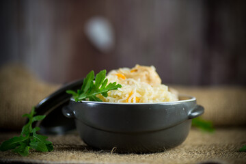 boiled rice with vegetables and meat in a ceramic bowl on a wooden table