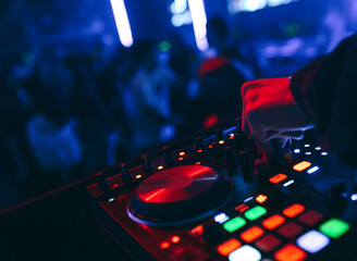 Fototapeta na wymiar producer DJ mixer in a nightclub with glowing plays musical rave Dubstep Electronic Trance composition with modern midi controller device in nightclub Live.Musical production process for artists.