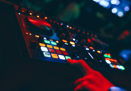 producer  DJ mixer in a nightclub with glowing plays musical rave Dubstep Electronic Trance composition with modern midi controller device in nightclub Live.Musical production process for artists.