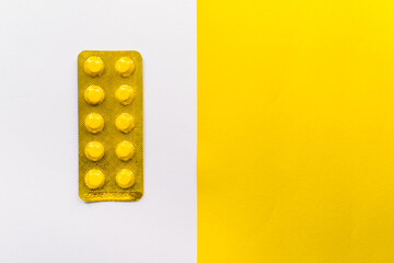 Tablets in packaging on white and yellow background.