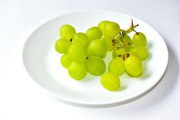 Green delicious ripe grapes on a white plate