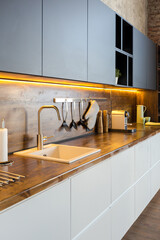 luxury studio apartment with a free layout in a loft style in dark colors. Stylish modern kitchen area with an island, cozy bedroom area with fireplace and personal gym