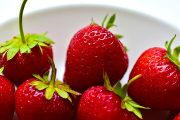 Large delicious Victoria berries and sliced Victoria berries on a white plate