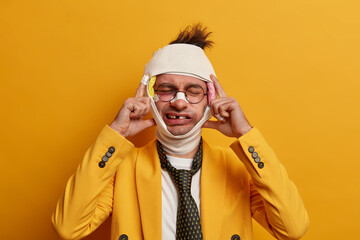 Photo of funny man has head injury, bruises under eyes after falling from height, keeps hands on...