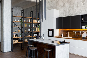 luxury studio apartment with a free layout in a loft style in dark colors. Stylish modern kitchen area with an island, cozy bedroom area with fireplace and personal gym