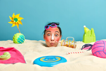 Photo of surprised Asian woman with sunburn facial skin, applies sunblock cream, has fun during...