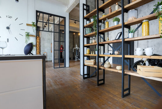 luxury studio apartment with a free layout in a loft style in dark colors. Stylish modern kitchen area with an island, cozy bedroom area with fireplace and personal gym