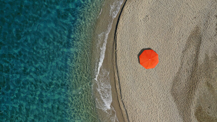 Aerial top down photo of beautiful turquoise Mediterranean secluded sandy bay forming a small peninsula with only one colourful sun umbrella enjoying summer © aerial-drone
