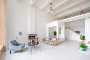 Luxury fashionable modern design studio apartment with a free layout in a minimal style. very bright huge spacious room with white walls and wooden elements. sitting area with fireplace