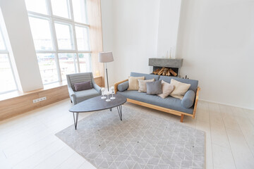 Fototapeta na wymiar Luxury fashionable modern design studio apartment with a free layout in a minimal style. very bright huge spacious room with white walls and wooden elements. sitting area with fireplace