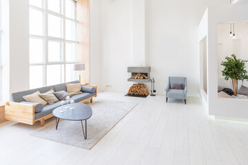 Fototapeta na wymiar Luxury fashionable modern design studio apartment with a free layout in a minimal style. very bright huge spacious room with white walls and wooden elements. sitting area with fireplace