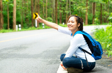young woman sitting hitchhiking on the road