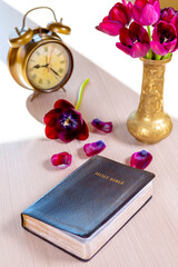 Holy Bible and old gold alarm clock with flowers