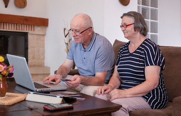 Senior couple shopping online using credit card on laptop
